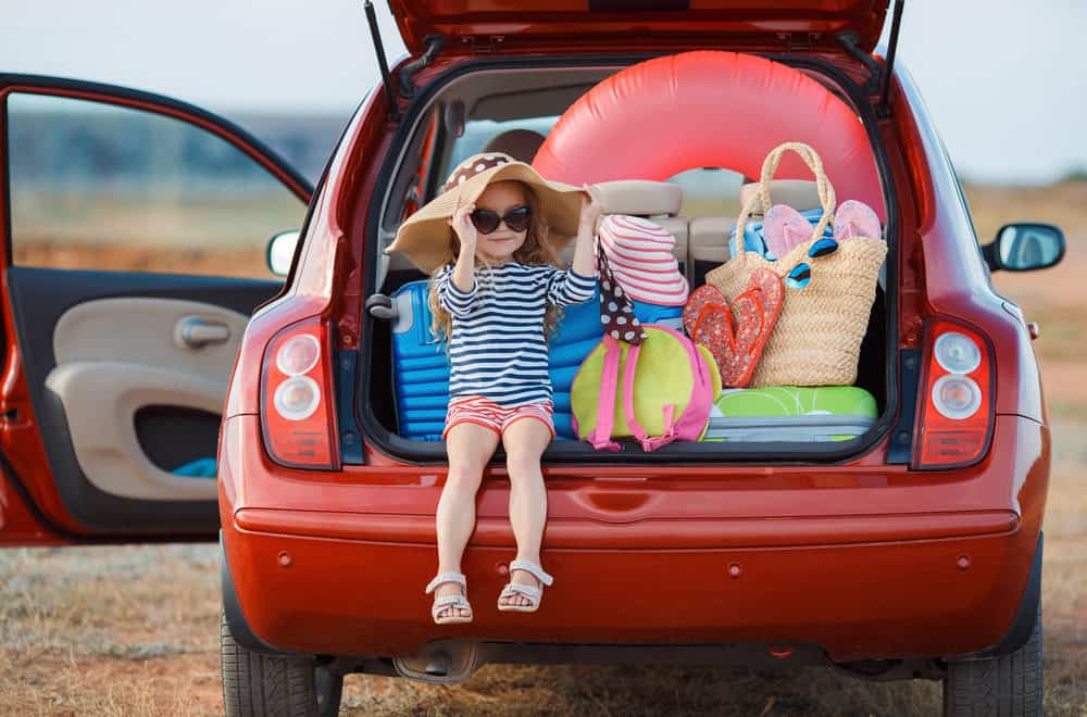 Girl sat in back of packed car - Self-catering holiday packing list