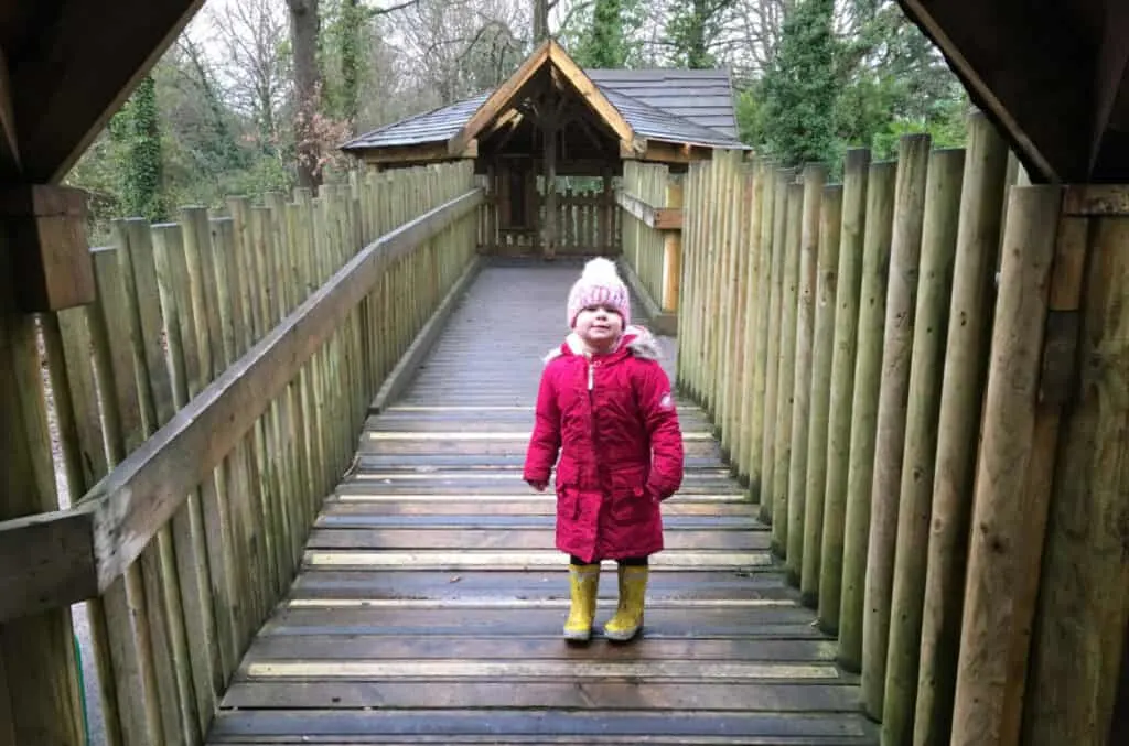 Child stood on walkway of accessible playground at Royal Victoria Country Park