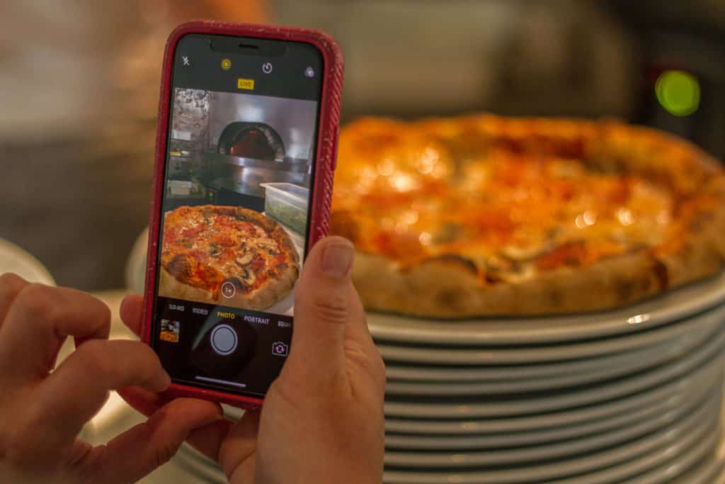 Claire using iPhone X to take a picture of pizza