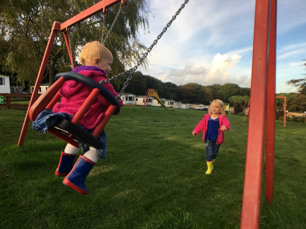 Tin Box girls playing on the swings at Trevella Holiday Park, Cornwall