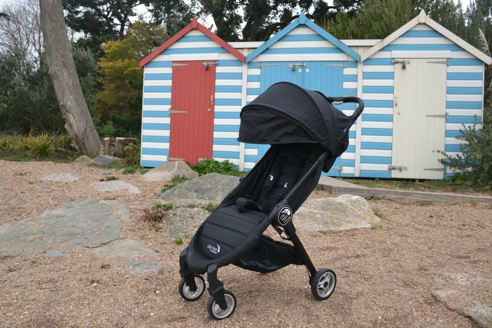 Stroller in front of beach huts - Stroller behind seats in car - Baby Jogger City Tour review - a great travel stroller