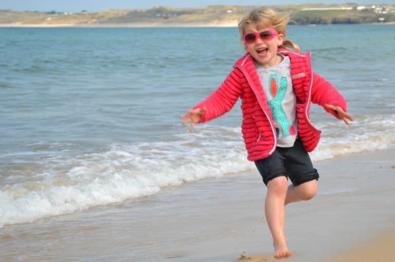 Tin Box Tot running away from waves at Carbis Bay - Woodland lodge resort for families: St Ives Holiday Village review