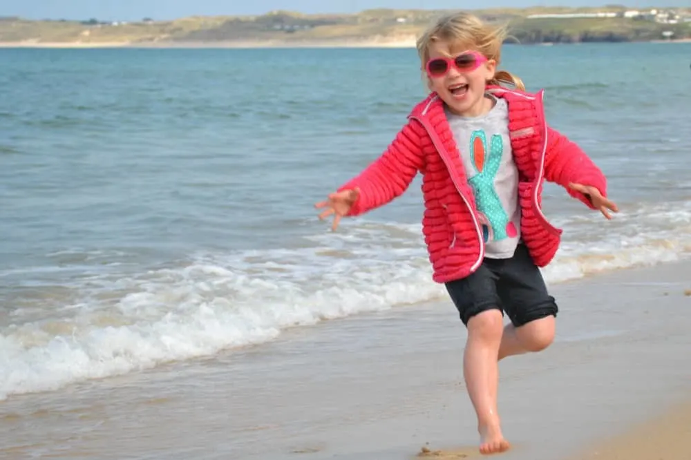 Tin Box Tot running away from waves at Carbis Bay - Woodland lodge resort for families: St Ives Holiday Village review