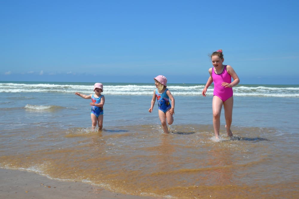 Kids running from waves on beach - Tin Box family and friend on water slide - caravan holiday in France, Al Fresco Holidays