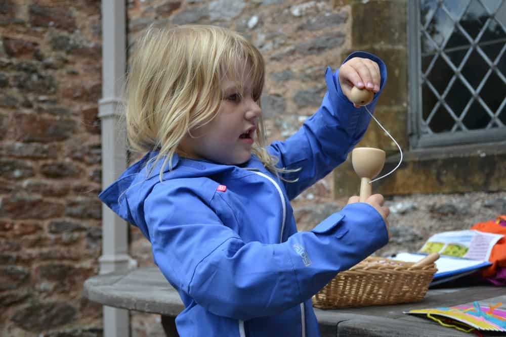 Tin Box Tot playing cup and ball game at Compton Castle Tudor Days