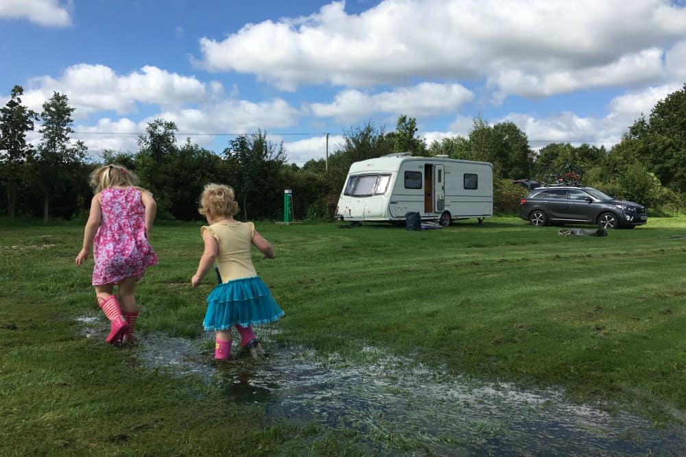 Tin Box girls paddling in puddle at Scotts Haven - A caravan holiday in England - our family road trip itinerary