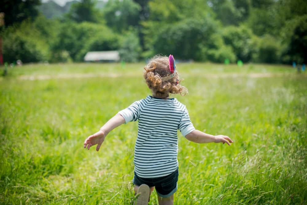 Girl running in field during Heligan Wild Week - May half term