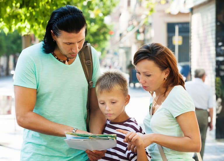 Traveling family looking at the map in city street - Created by Bearfotos - Freepik.com