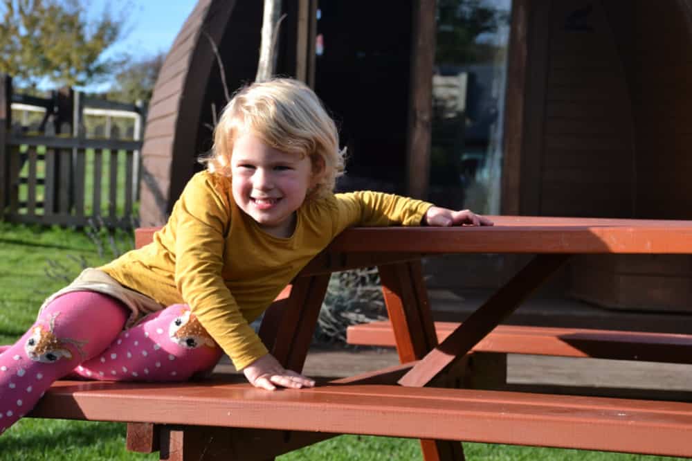 Baby on picnic bench outside Fox Pod - Stonehenge Campsite review