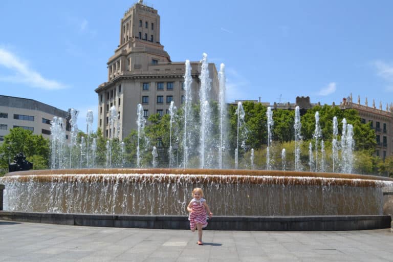 Toddler running in front of fountain in Barcelona - how to have a stress-free city break with toddlers