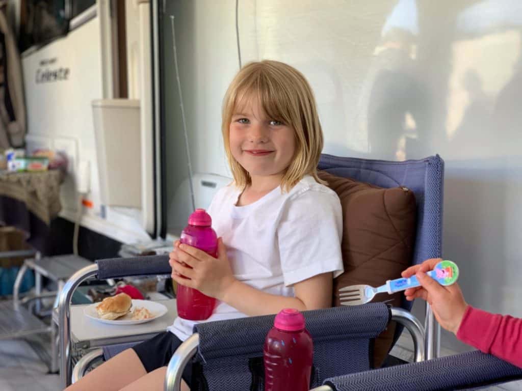 Tot having a barbecue dinner in caravan awning