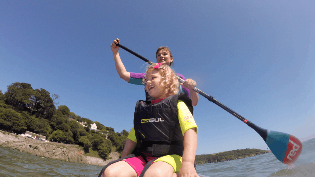 Riding a paddle board with a kid in Devon