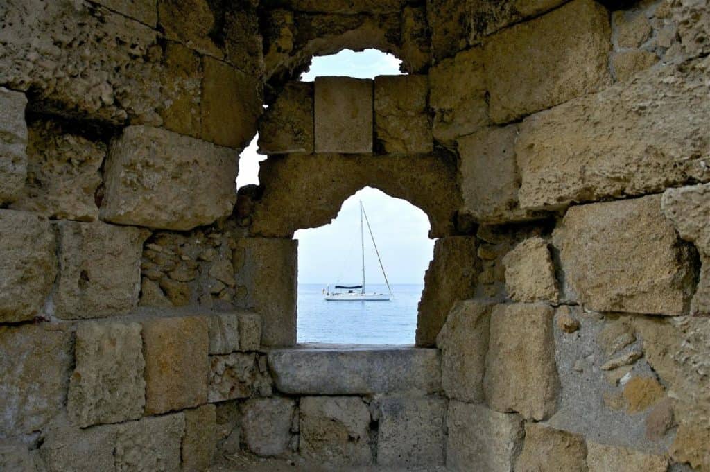 Sailing boat in Greece viewed through stone wall
