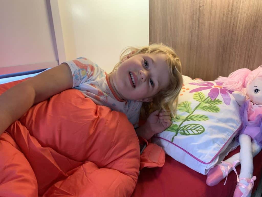 Child in sleeping bag on caravan bunk bed