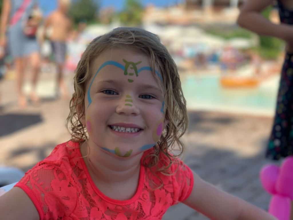 Child with face painted beside outdoor pool at Norcenni Girasole