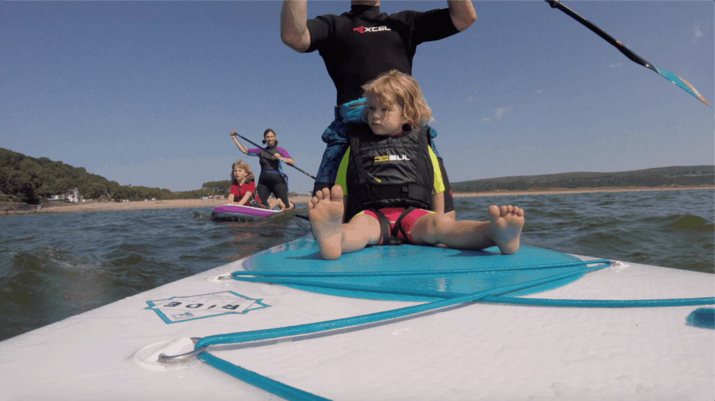 Family using inflatable stand up paddle boards on the sea