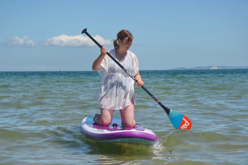 Kneeling on inflatable stand up paddle board on sea