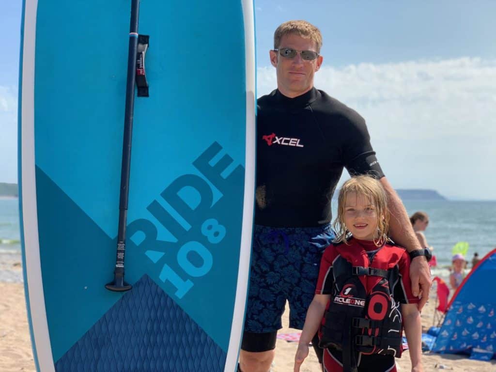 Tot and Mr Tin Box standing with a 10'8" Ride inflatable stand up paddle board