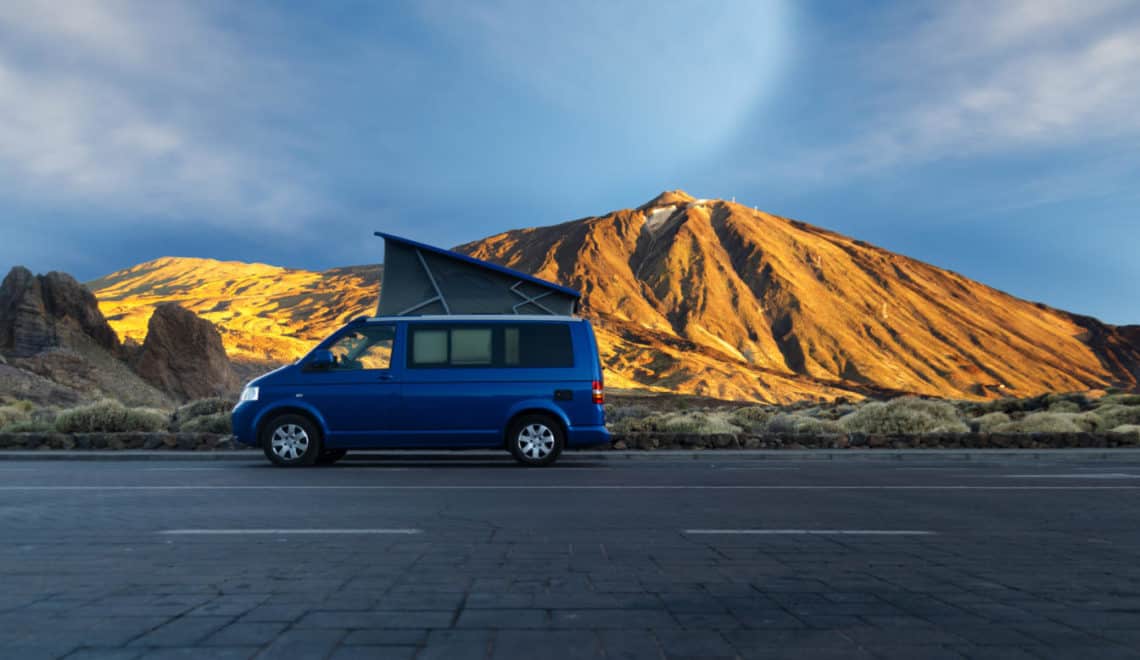 VW camper van with pop top against mountain background - buying a camper van