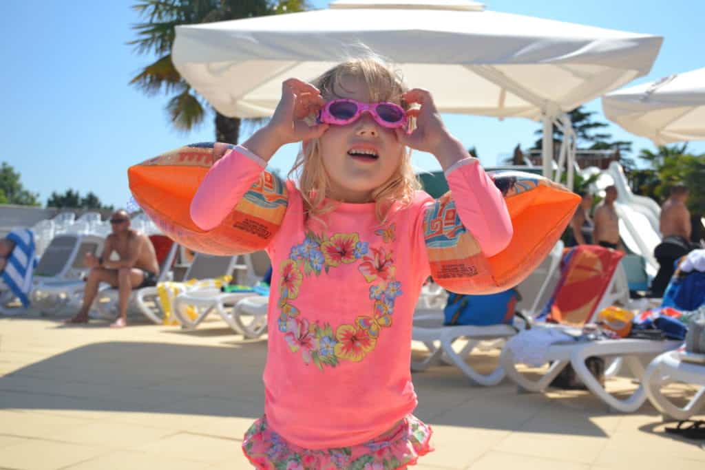 Child wearing Sunuva swimwear and googles by pool