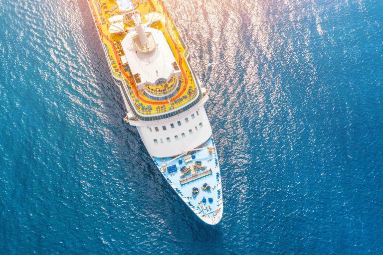 Nose of the cruise ship in the turquoise sea, with a glare from the sun on the water. Concept of summer sea cruise tours