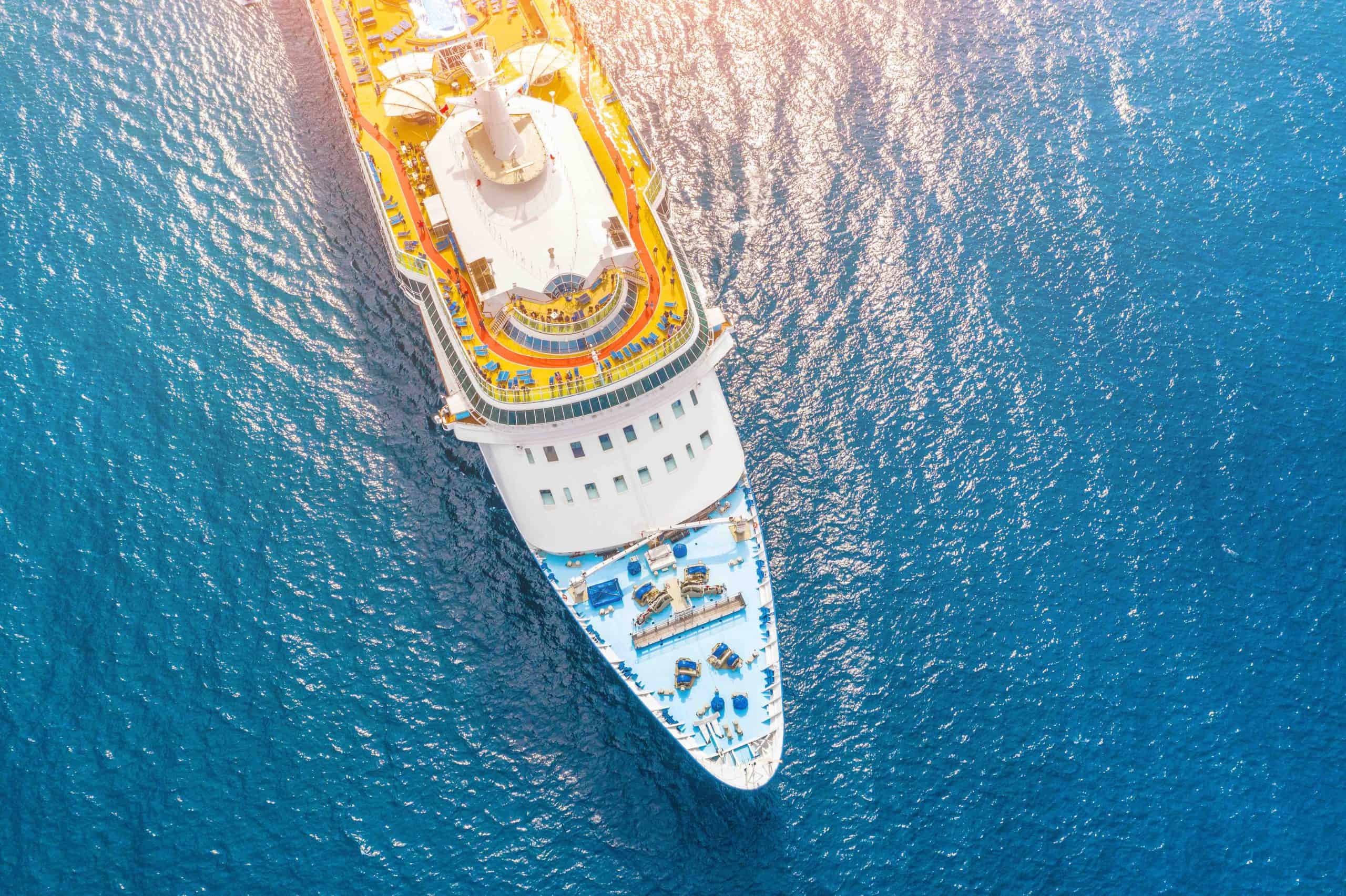 Nose of the cruise ship in the turquoise sea, with a glare from the sun on the water. Concept of summer sea cruise tours