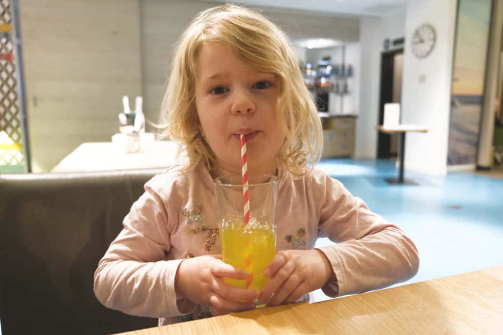 Blowing bubbles in a glass of orange squash