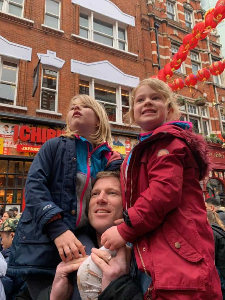 Children sat on dad's shoulders in Chinatown, London