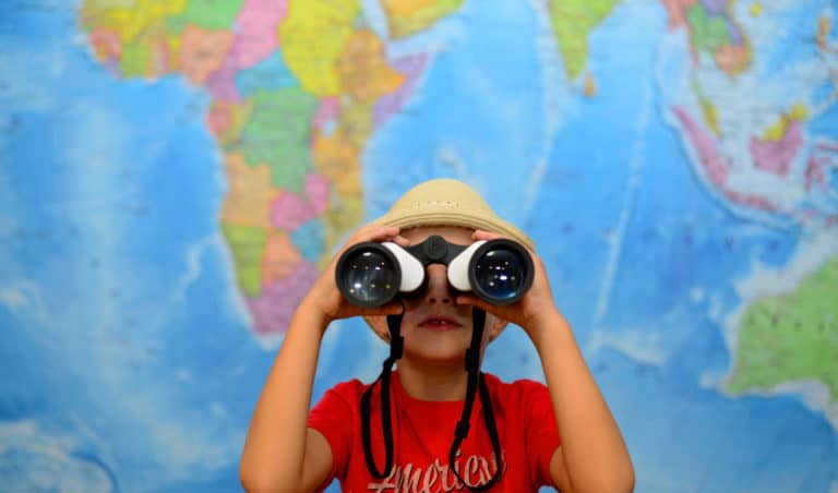 Boy with binoculars in front of world map