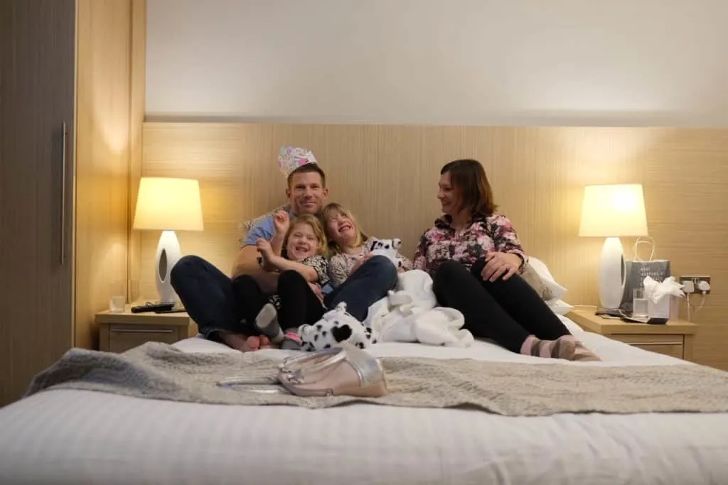 Family cuddled on hotel bed
