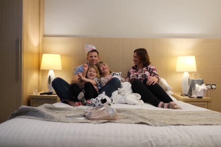 Family cuddled on hotel bed