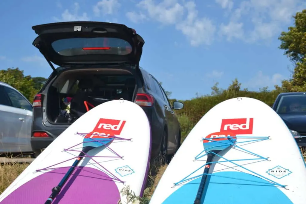 Red paddle boards proper up next to parked car