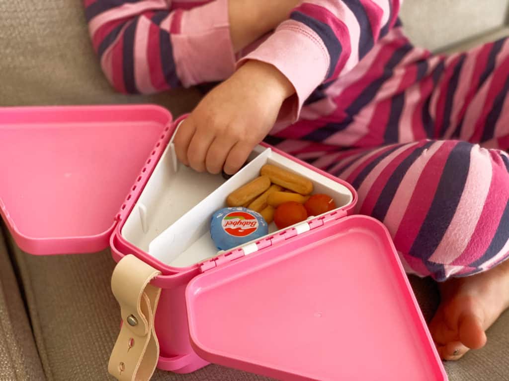 Child's hand reaching into tray for a snack