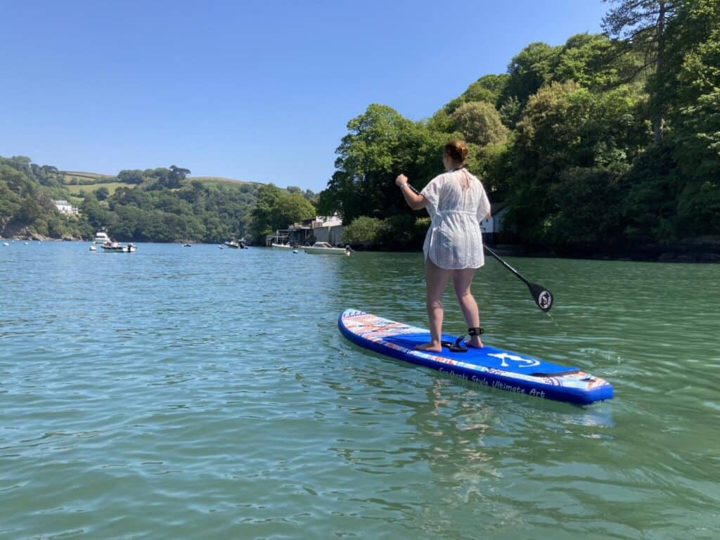 Claire standing on paddle board in river