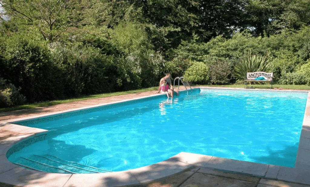 Child sat dangling legs into swimming pool