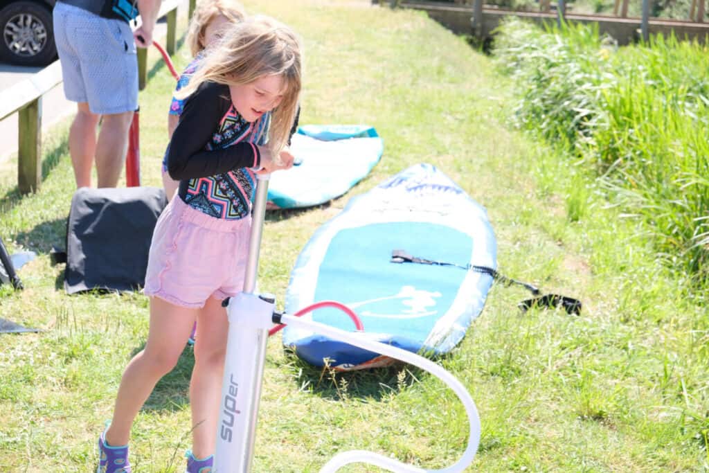 Tot pumping up a stand up paddle board on grass
