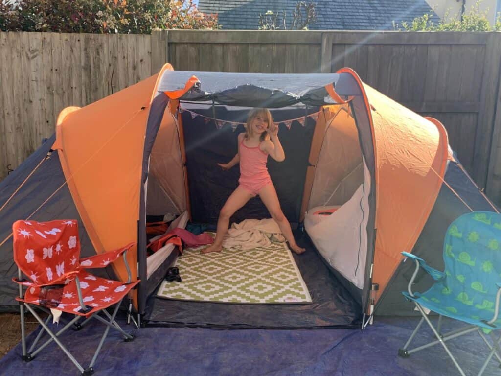 Tot playing in tent pitched in garden at home
