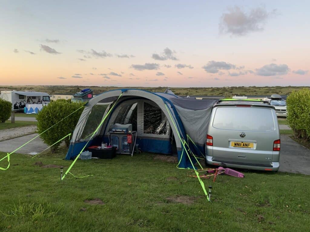 VW T5 camoer van and OLPRO Cocoon Breeze Air Beam camper van air awning on campsite pitch at sunset