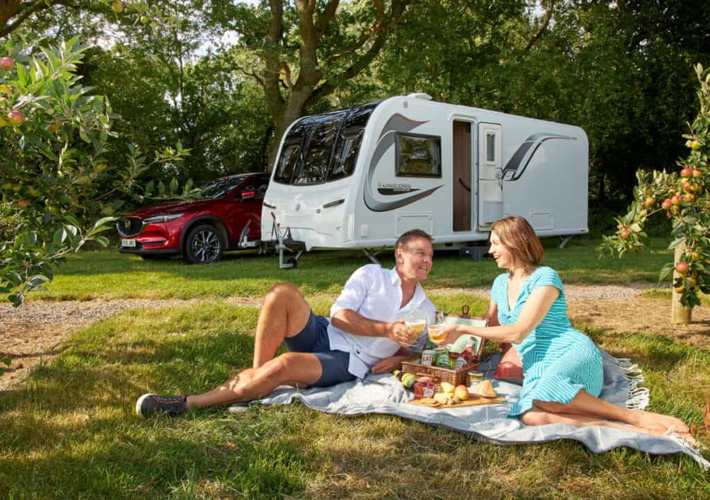 Couple haven picnic outside a Bailey Unicorn Black Edition caravan