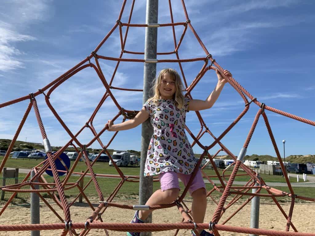 Tot playing on climbing frame on campsite playground