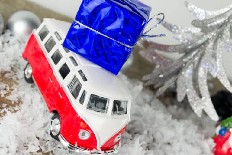 Toy camper van with gift on top in snowy scene