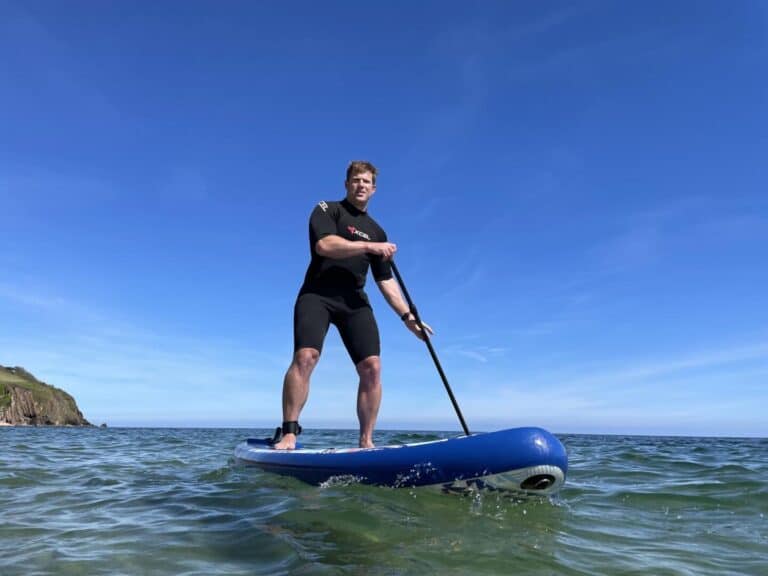 Mr Tin Box paddle boarding along South Devon coast on a sunny day