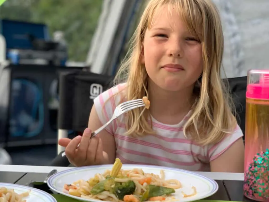 Child eating stir fry while camping