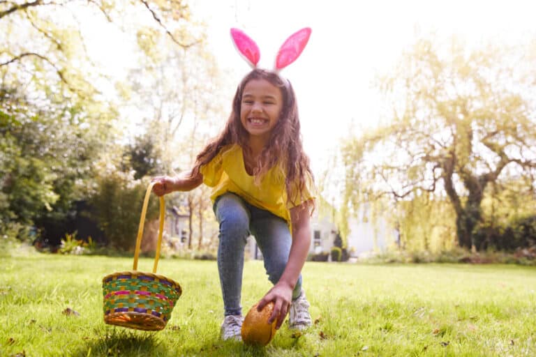 Girl wearing bunny ears on Easter egg hunt in garden