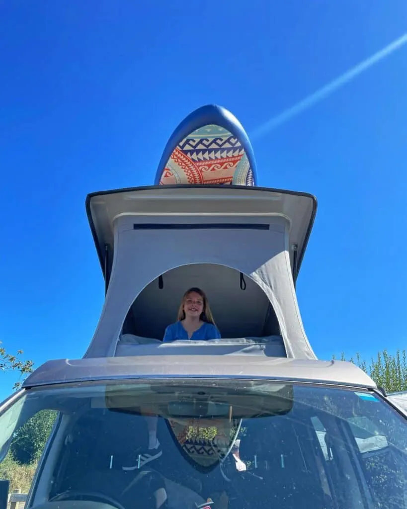 Girl looking out lot front window of camper van pop top