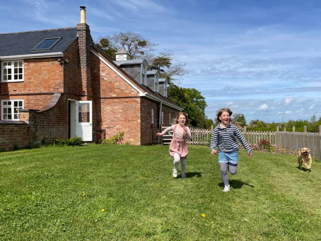 Children running in garden outside cottage