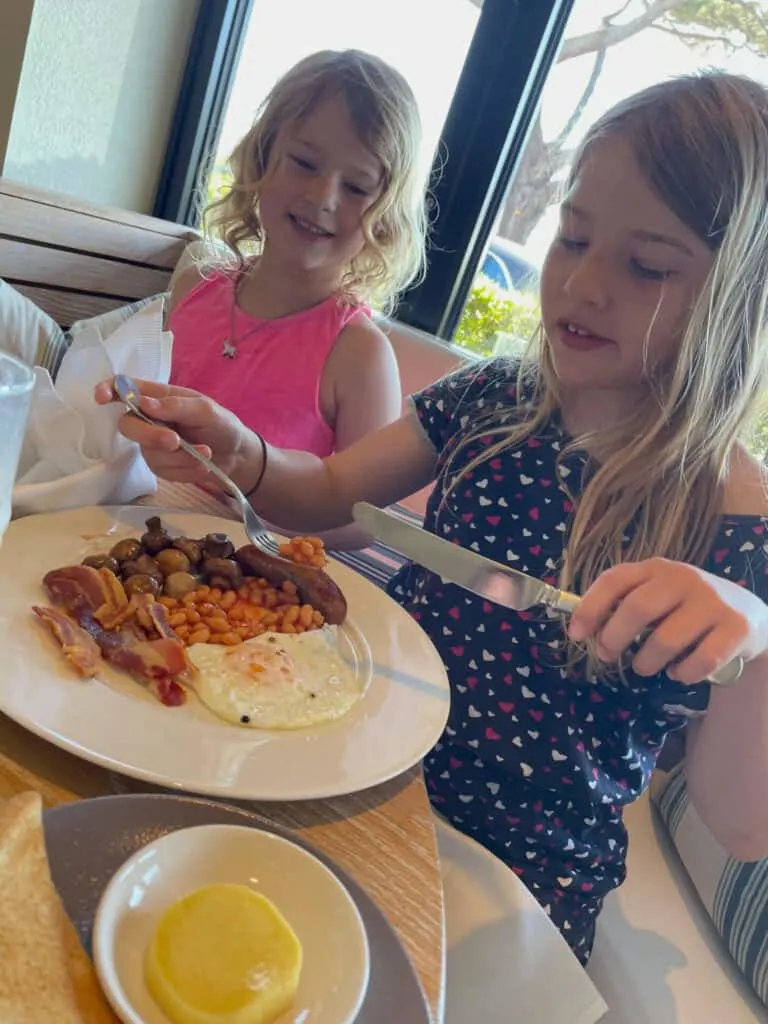 Girls enjoying full English breakfast with beans at Rick Steins in Sandbanks