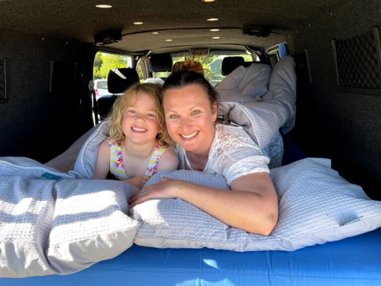 Mum and child in duvet in the back of a camper van