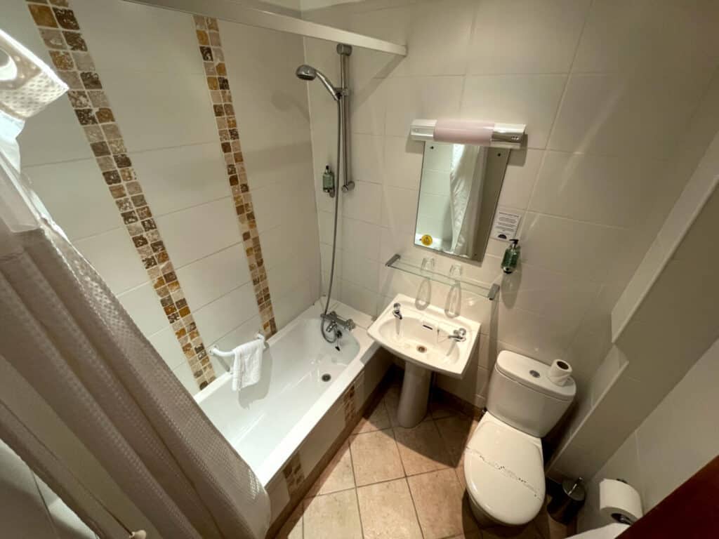 Ensuite bathroom with shower over bath, sink and toilet