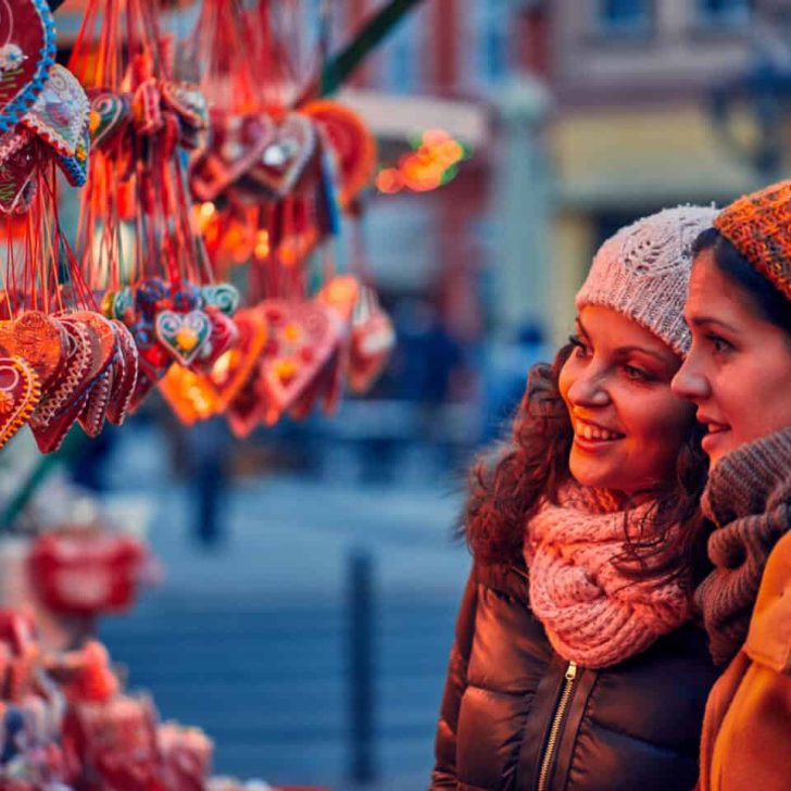Friends looking at decorated biscuits at a Christmas market
